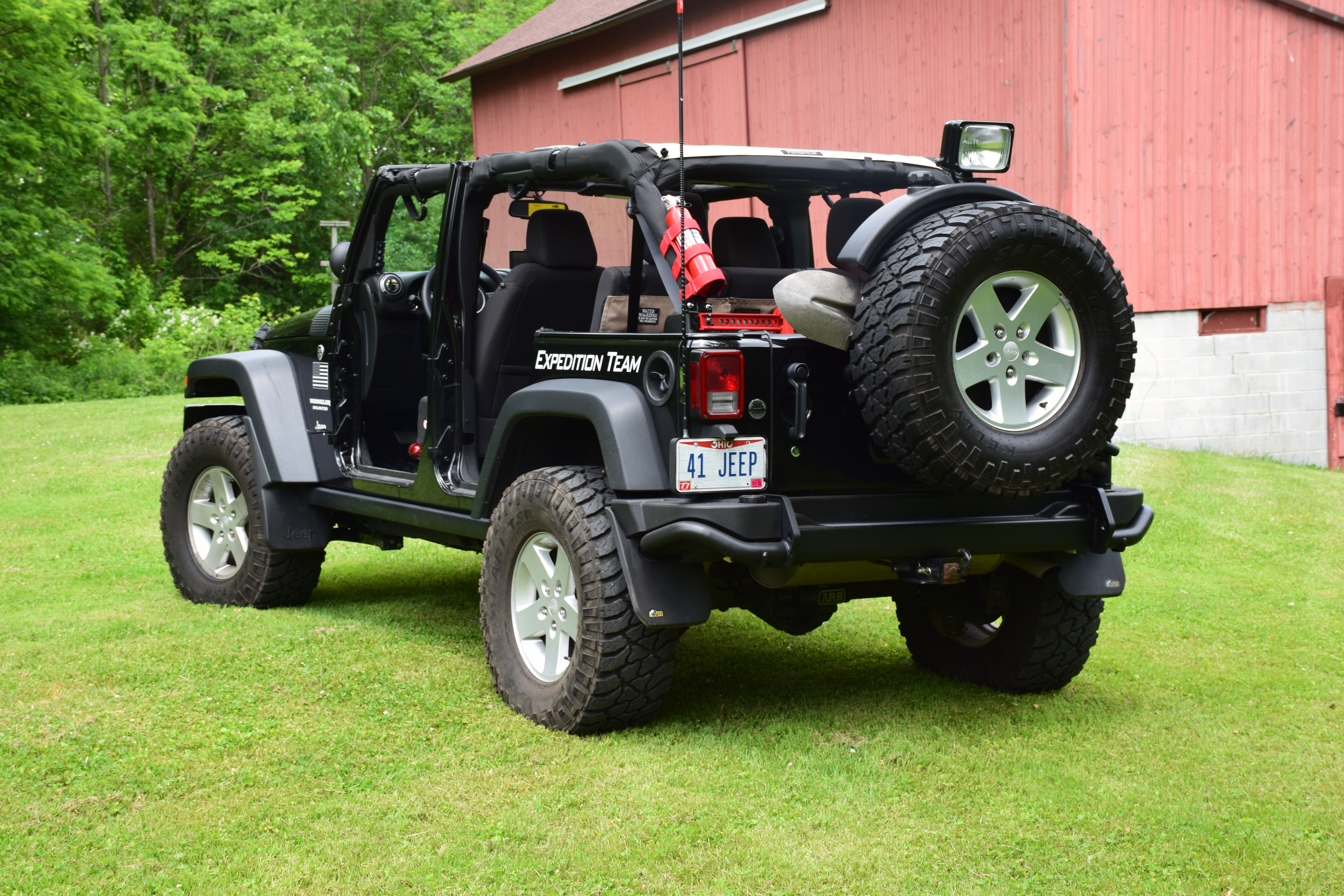 Rear three-quarter view of the open 2013 Jeep Wrangler with full-size spare and trail equipment