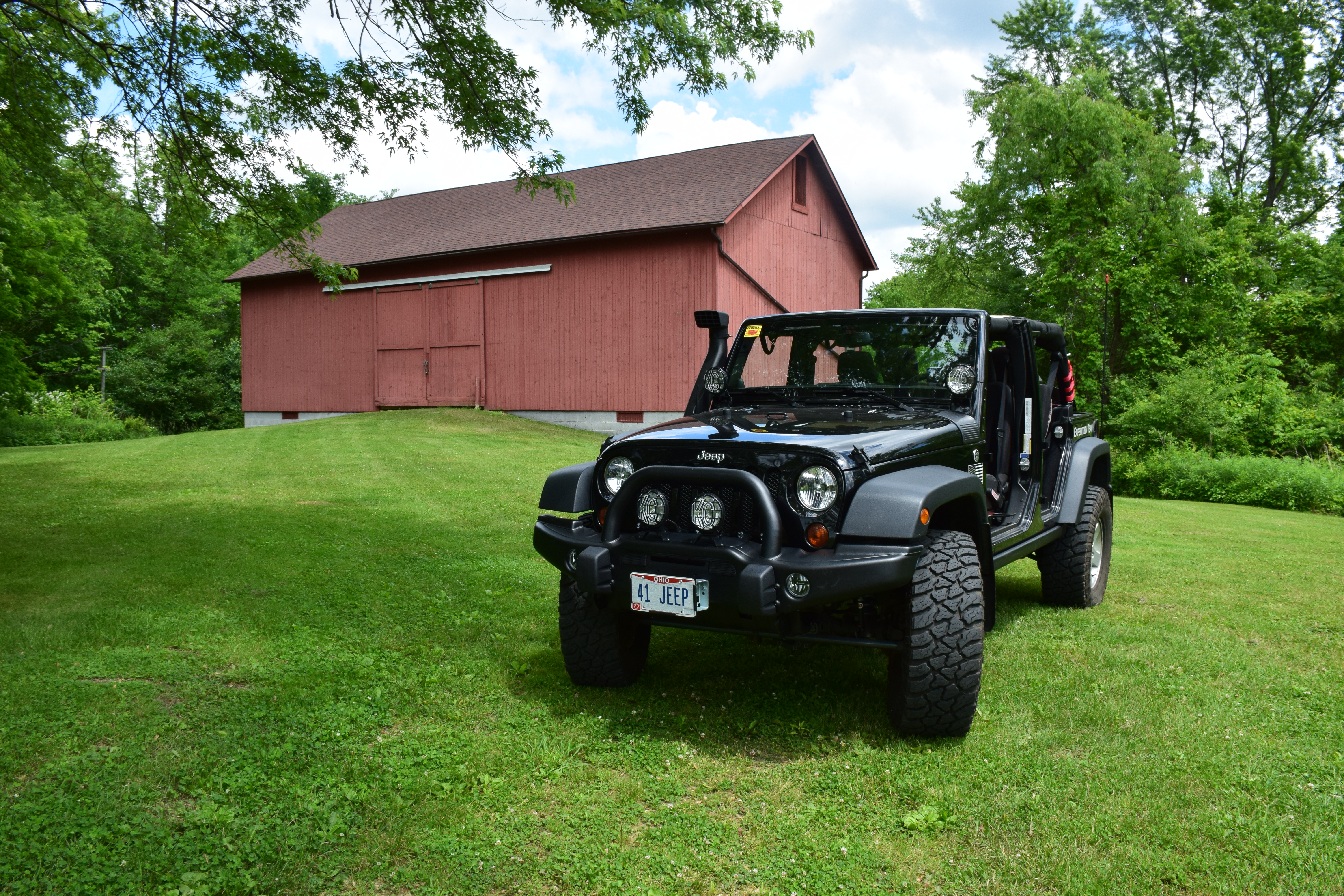 Wide environmental portrait of the Wrangler near a red barn