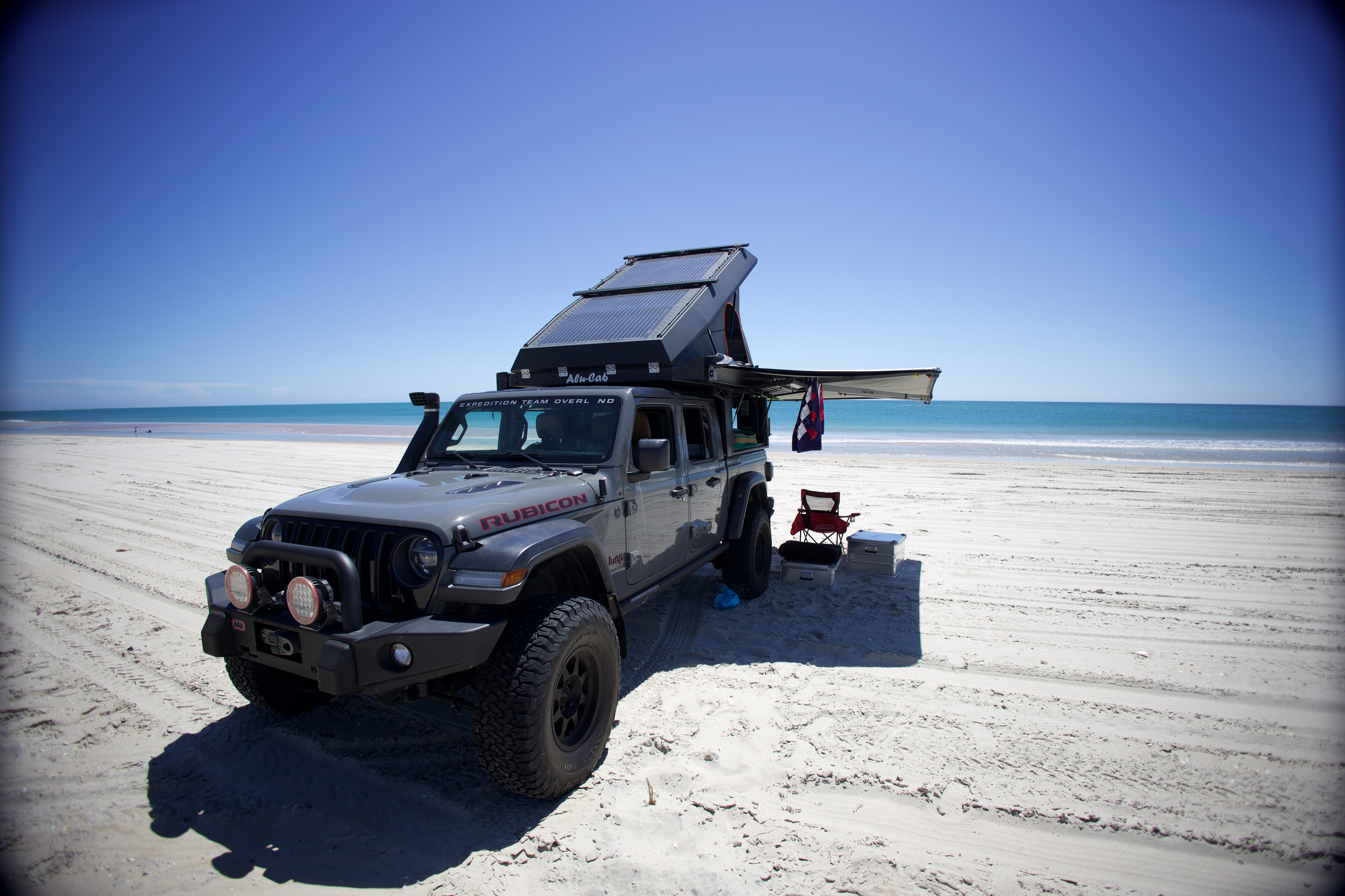 Expedition Team Overland Jeep Gladiator camper set up on a wide beach