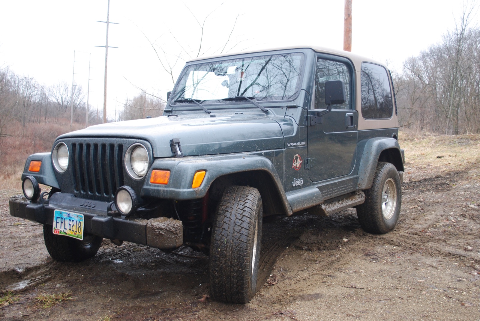 Green and tan Jeep Wrangler Sahara after a muddy trail drive