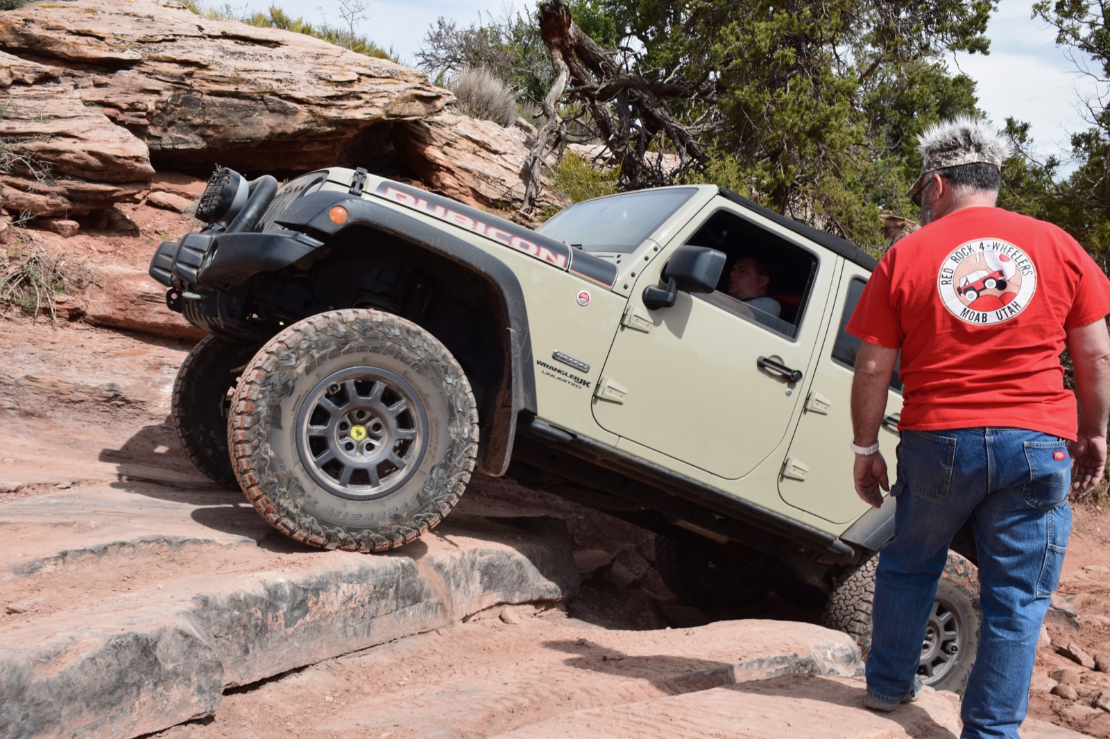Jeep Wrangler climbing a sandstone ledge with a trail guide in Moab